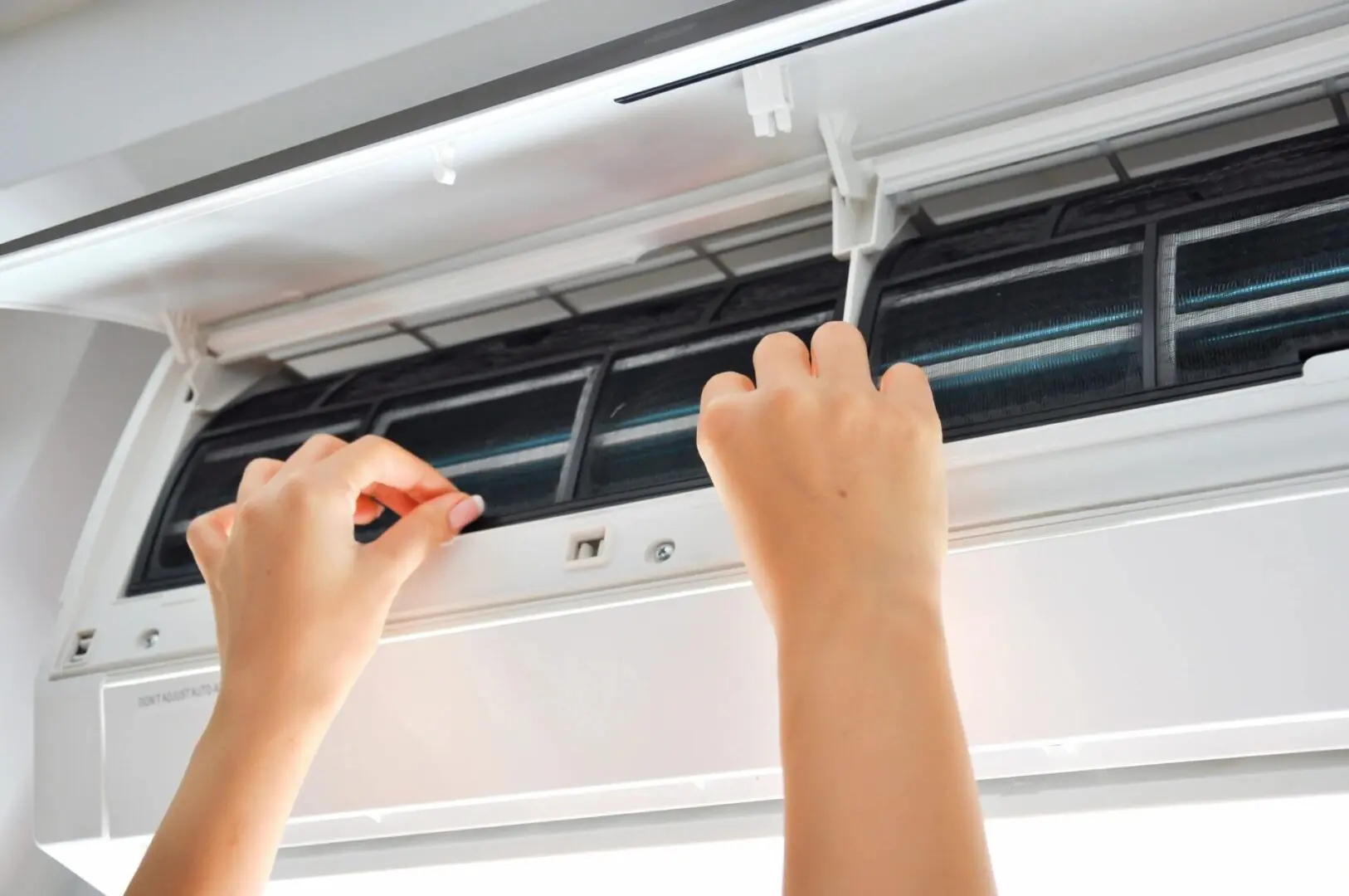 A person is adjusting the air conditioner 's temperature.