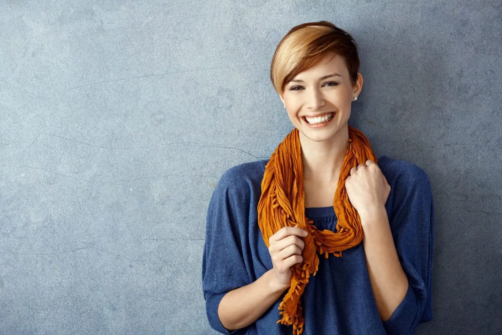 A woman with short hair and wearing an orange scarf.