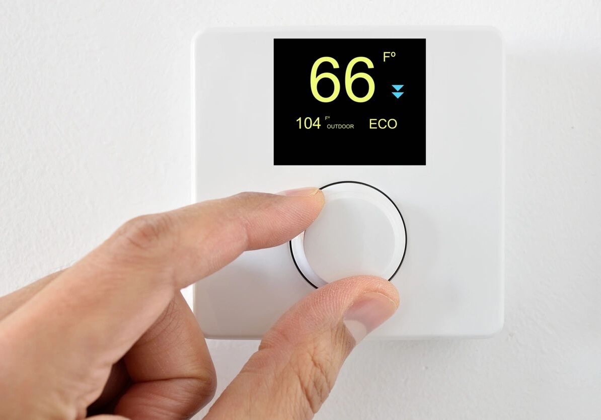 A person is adjusting the temperature on an electronic thermostat.